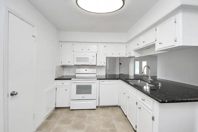 a kitchen with granite countertop a sink a stove and cabinets