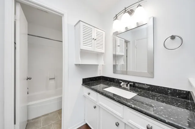 a bathroom with a granite countertop sink and a mirror