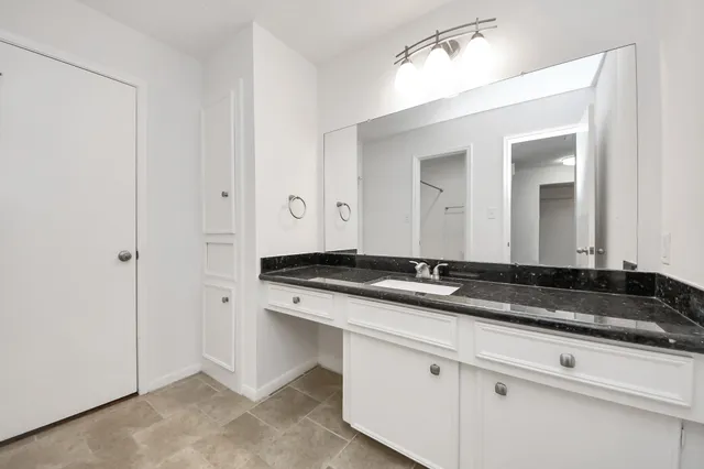a bathroom with a granite countertop sink and a mirror