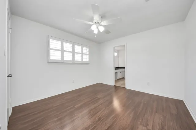 an empty room with wooden floor chandelier fan and windows