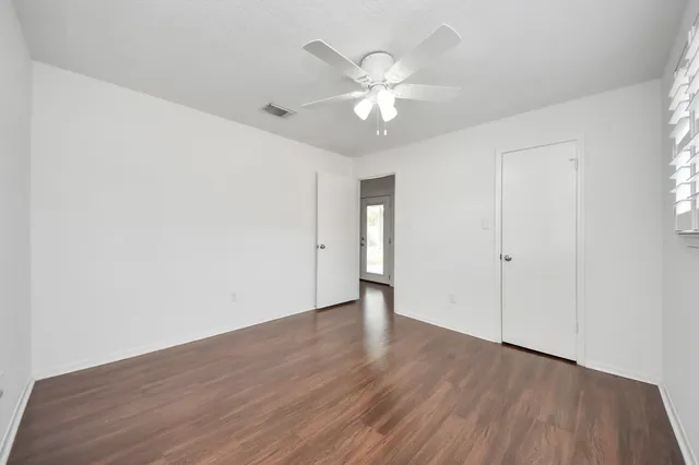 an empty room with wooden floor and fan