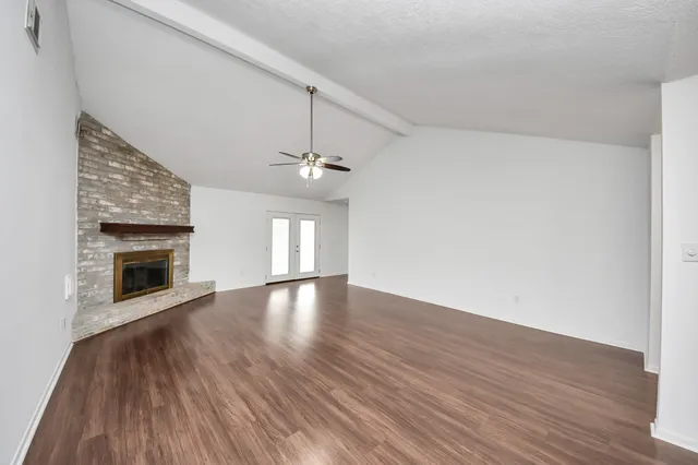 an empty room with wooden floor fireplace and windows