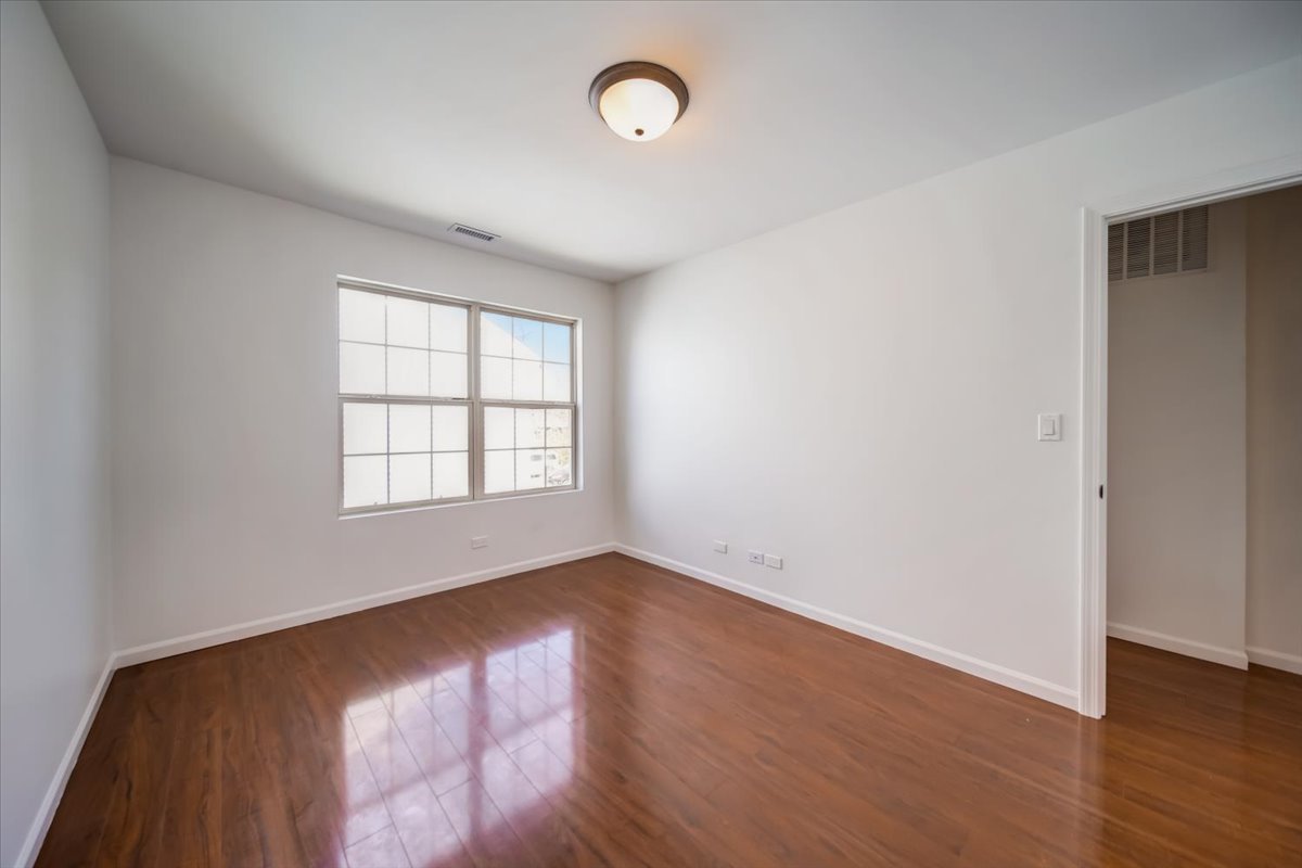 2414 West Harrison Street, Unit E Chicago, IL 60612 - Photo 17 of 37 an empty room with wooden floor and windows