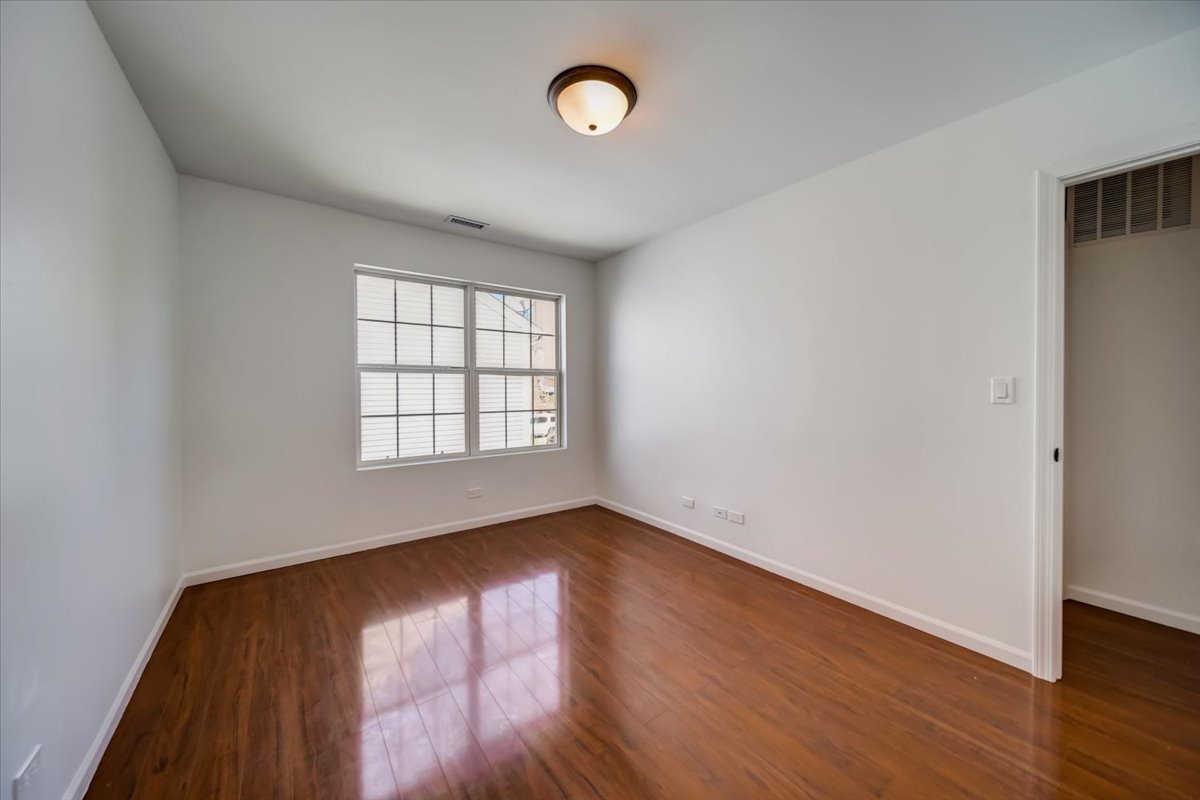 2414 West Harrison Street, Unit E Chicago, IL 60612 - Photo 21 of 37 an empty room with wooden floor and windows