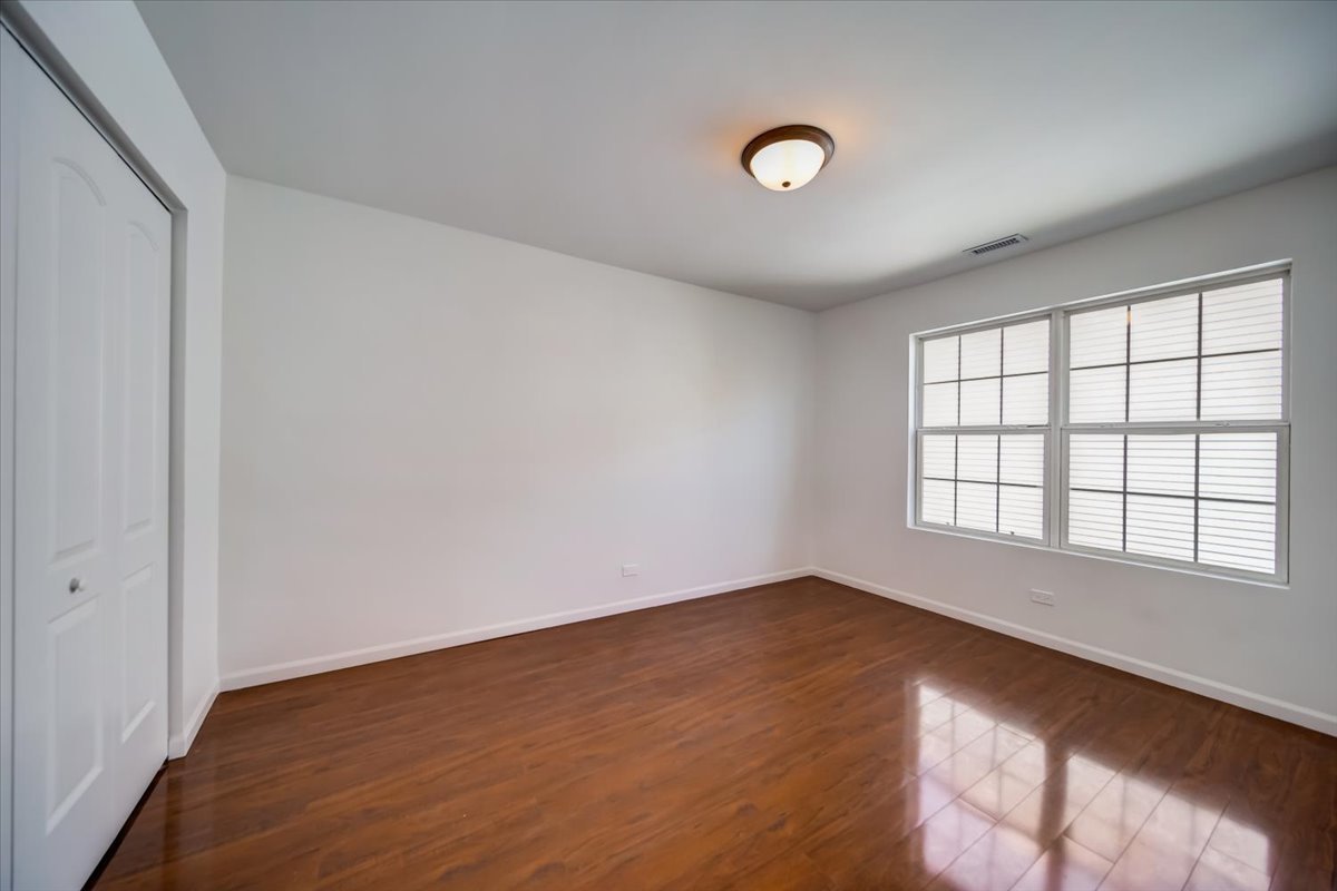 2414 West Harrison Street, Unit E Chicago, IL 60612 - Photo 22 of 37 an empty room with wooden floor and windows