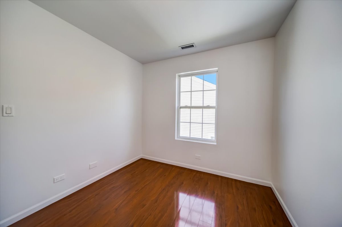 2414 West Harrison Street, Unit E Chicago, IL 60612 - Photo 25 of 37 an empty room with wooden floor and windows
