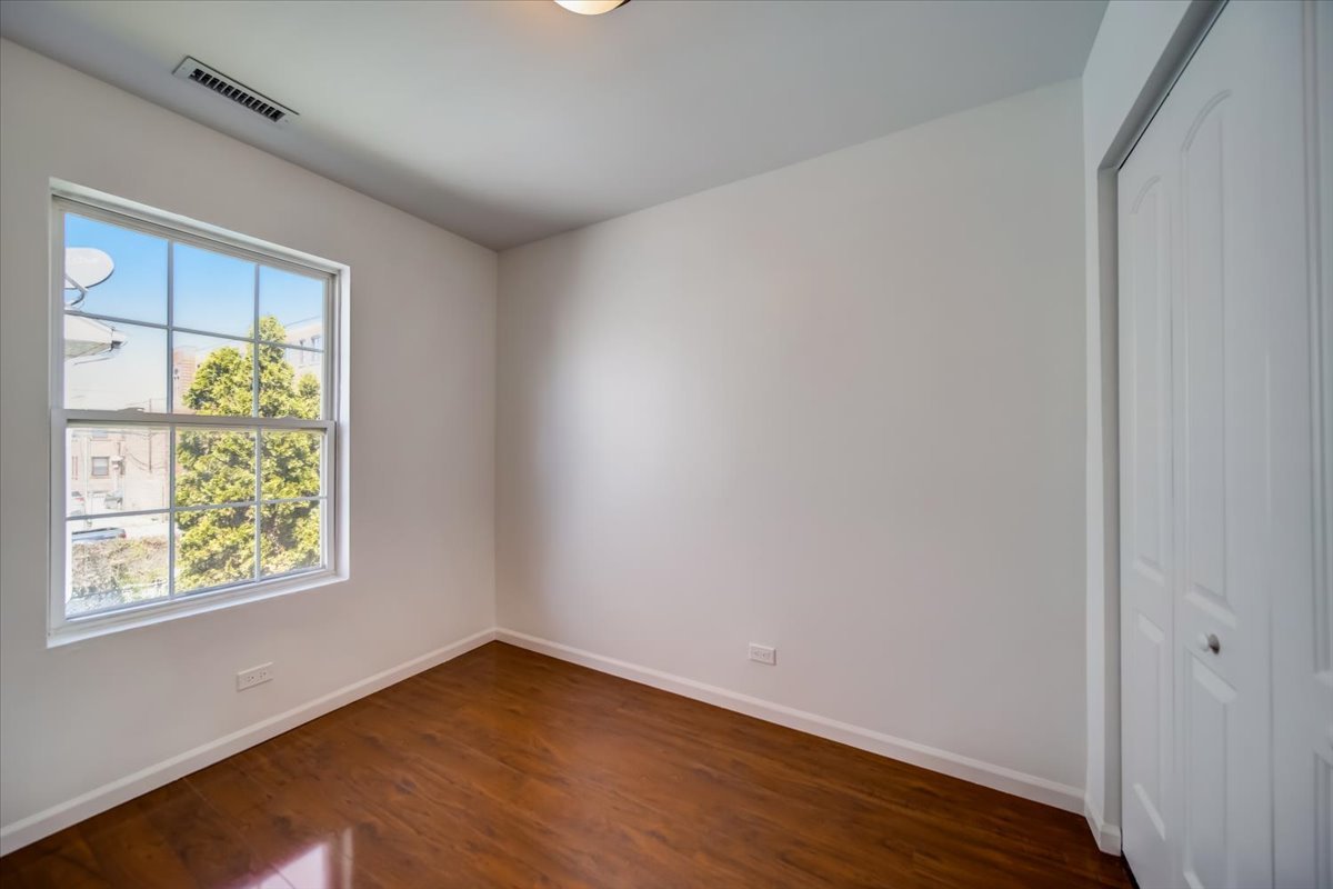 2414 West Harrison Street, Unit E Chicago, IL 60612 - Photo 26 of 37 an empty room with wooden floor and windows