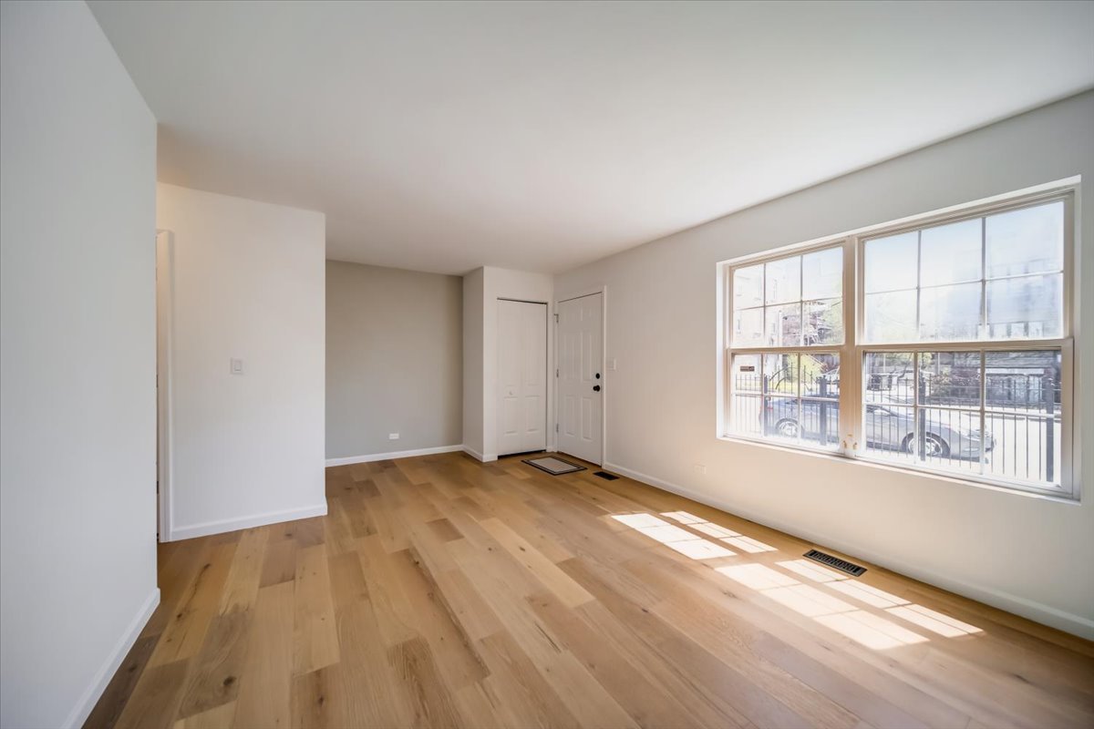 2414 West Harrison Street, Unit E Chicago, IL 60612 - Photo 3 of 37 an empty room with wooden floor and windows