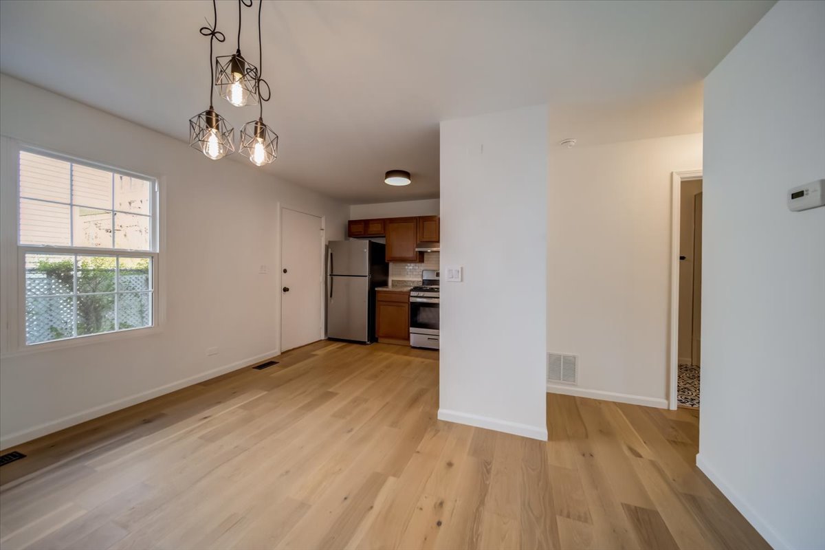 2414 West Harrison Street, Unit E Chicago, IL 60612 - Photo 8 of 37 an empty room with wooden floor chandelier and windows