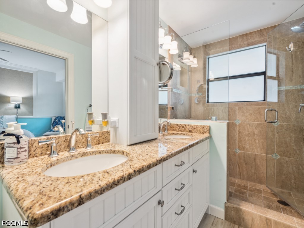 232 La Peninsula Boulevard, Unit 232 Naples, FL 34113 - Photo 21 of 44 a bathroom with a granite countertop sink a mirror and a shower