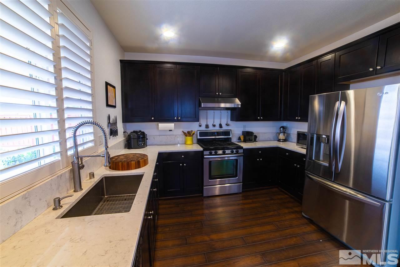 11435 Rivolli Court Reno, NV 89521 - Photo 8 of 23 a kitchen with kitchen island granite countertop a refrigerator a sink a stove a microwave and wooden cabinets