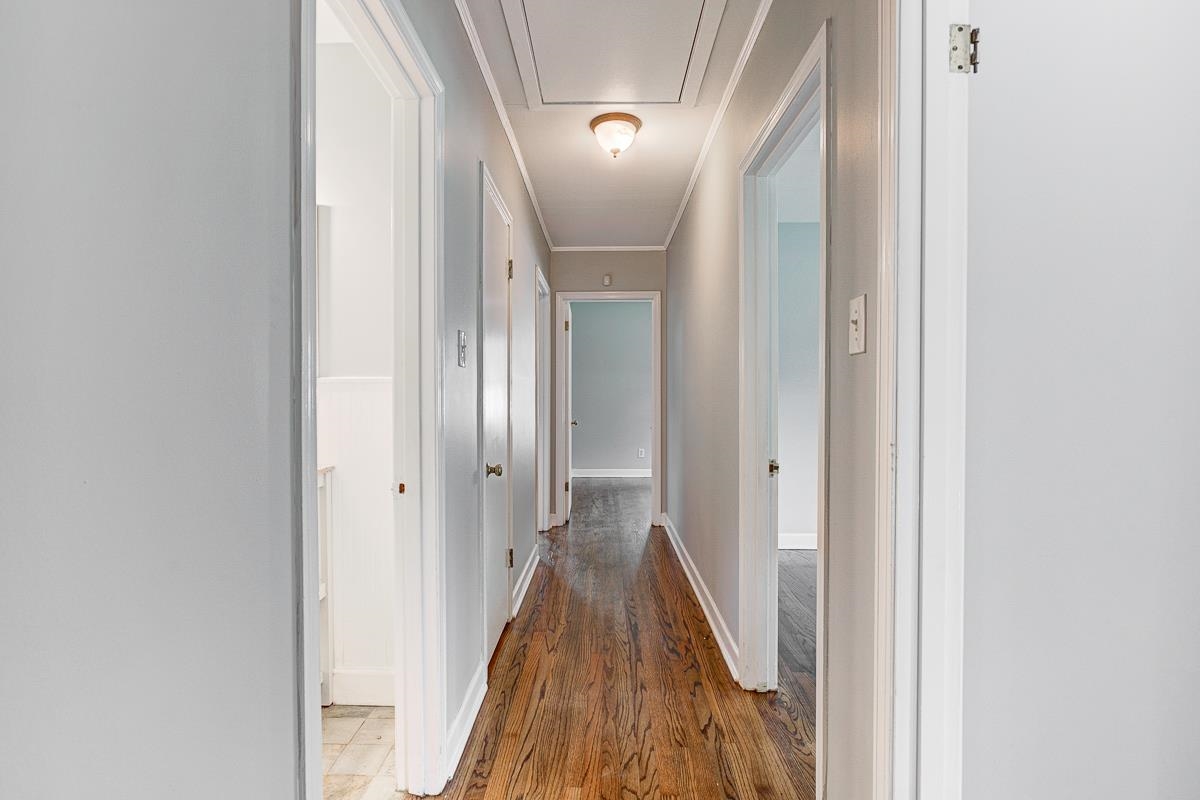 5676 Barfield Road Memphis, TN 38120 - Photo 11 of 19 Long hallway featuring wood-finish flooring, light gray walls, and multiple white doors