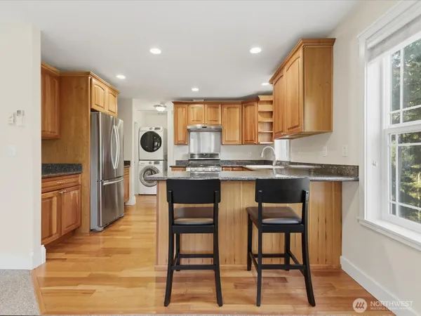 a kitchen with stainless steel appliances granite countertop a stove a sink a refrigerator with a dining table and chairs