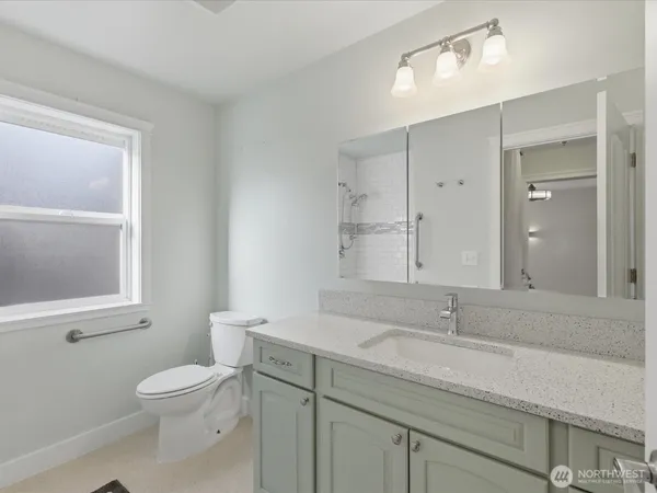 a bathroom with a toilet a sink a mirror and a window