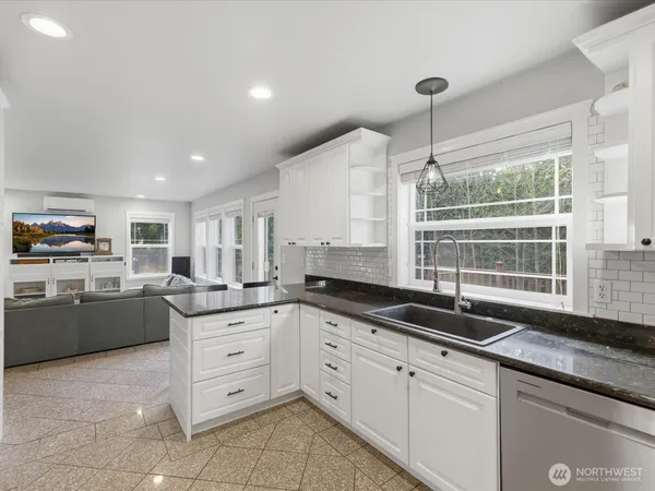 a kitchen with granite countertop a sink and white cabinets