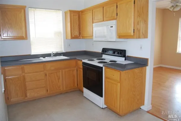 a kitchen with granite countertop cabinets stainless steel appliances a sink and a window