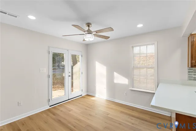 a view of an empty room with a window and wooden floor