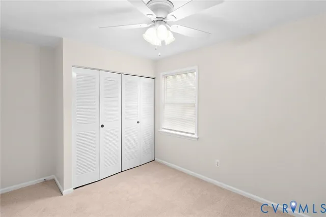 an empty room with chandelier fan and windows