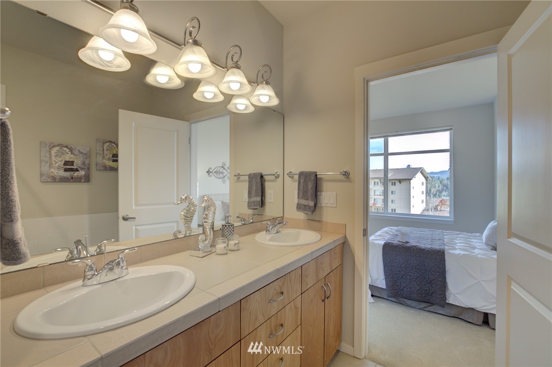 114 Cougar Ridge Road Northwest, Unit 1701 Issaquah, WA 98027 - Photo 11 of 25 a bathroom with a granite countertop sink a large mirror and a shower