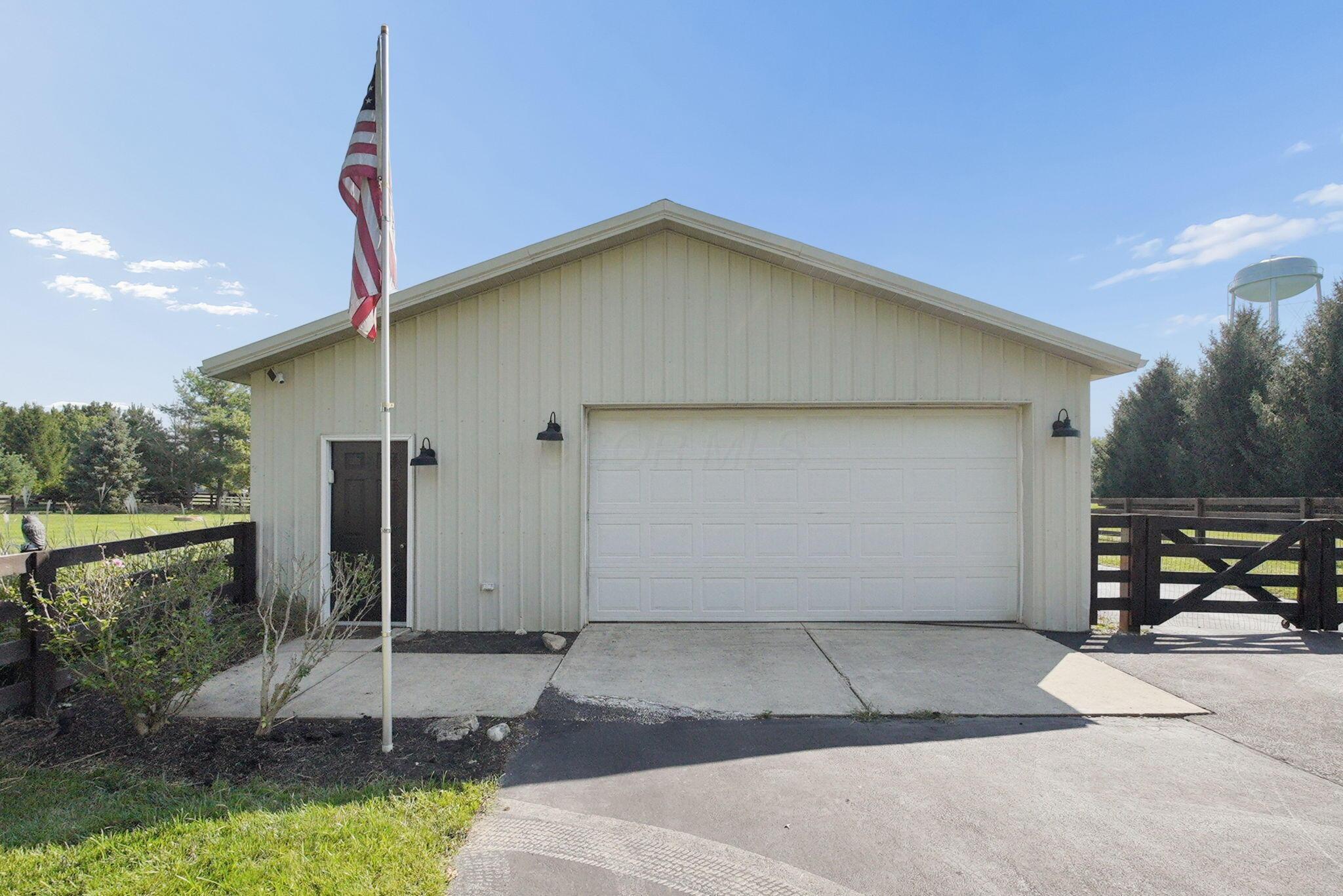 9435 Concord Road Powell, OH 43065 - Photo 49 of 77 Detached garage building featuring a white panel garage door, exterior lighting fixtures, and a side entry door