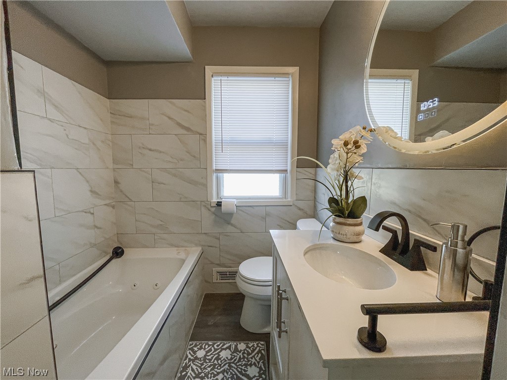 24709 Emery Road Warrensville Heights, OH 44128 - Photo 7 of 34 Bathroom with a tub, oversized vanity, tile walls, toilet, and tile floors