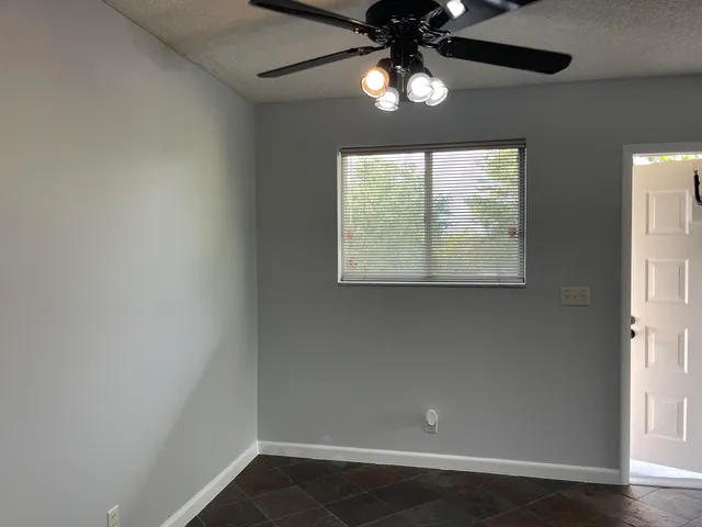an empty room with wooden floor chandelier and windows