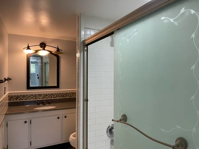a bathroom with a granite countertop sink a toilet and mirror