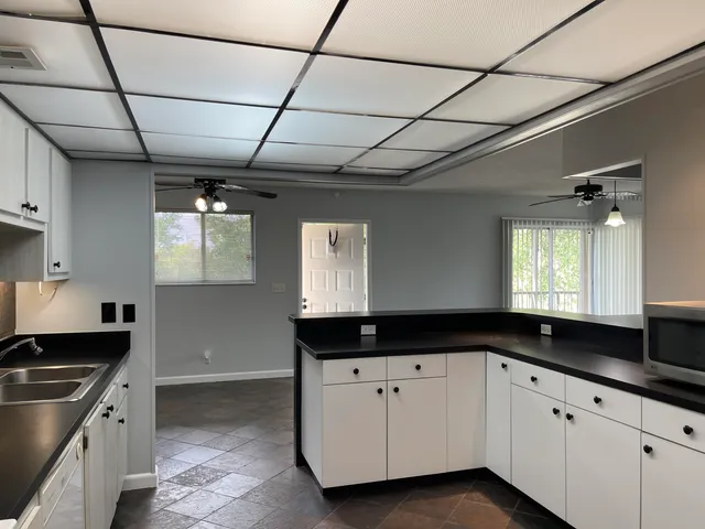 a kitchen with granite countertop a sink a stove cabinets and a window