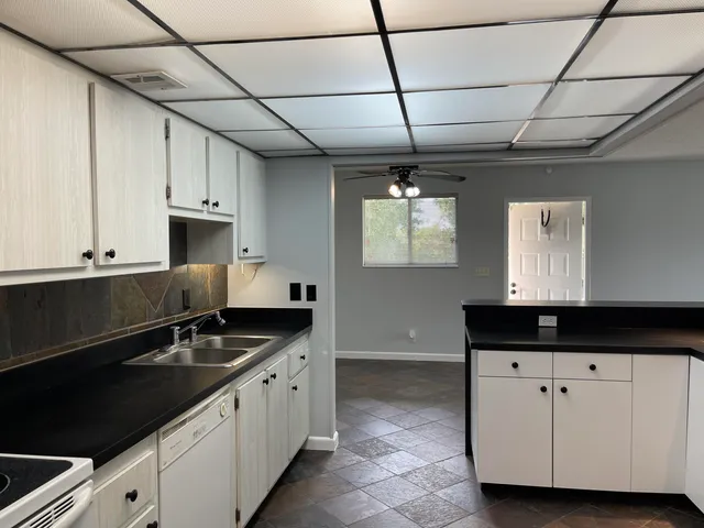 a kitchen with granite countertop a sink a stove and cabinets