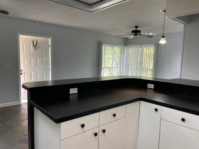 a kitchen with granite countertop white cabinets and black appliances