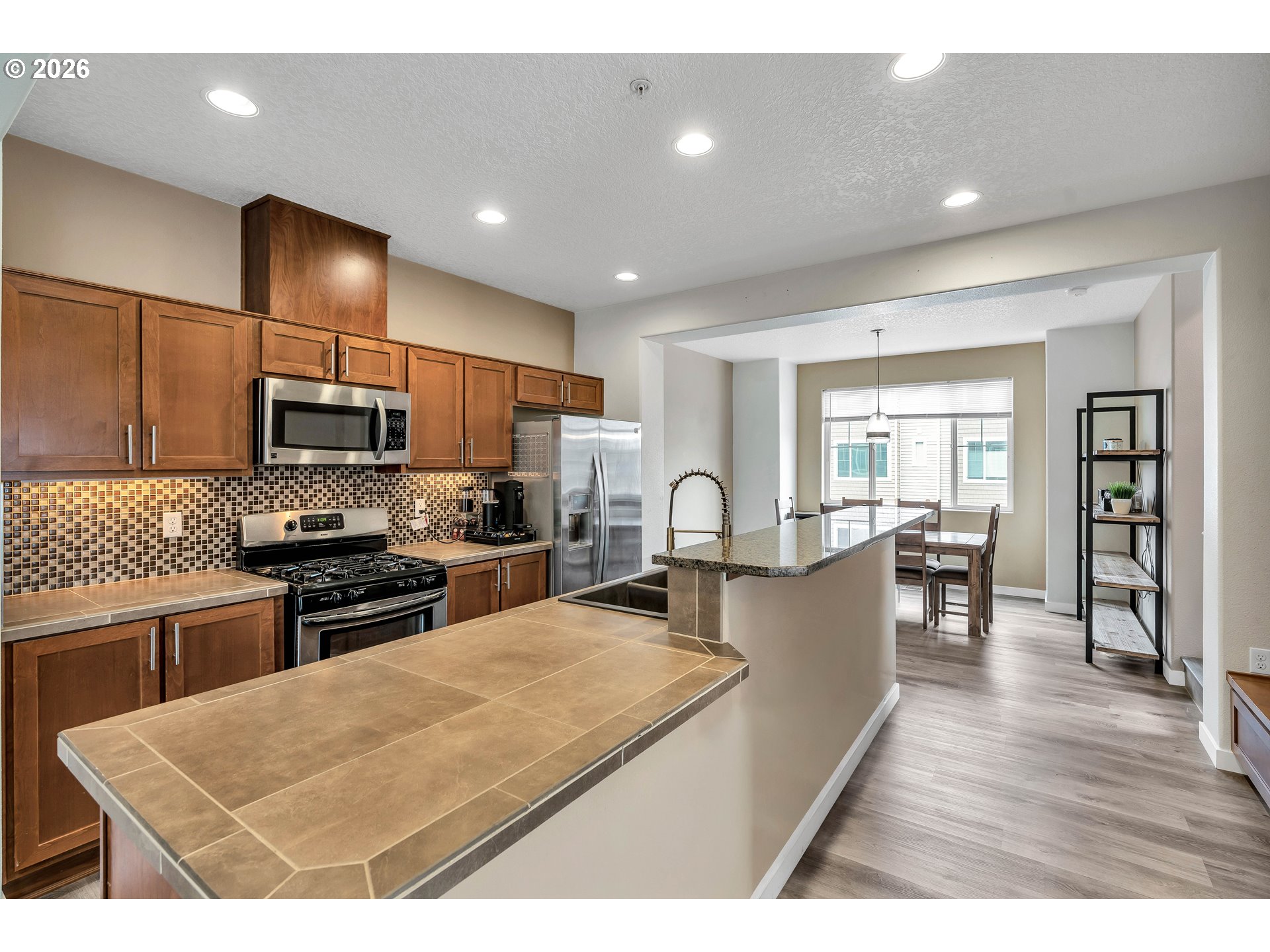 350 Northwest 116th Avenue, Unit 101 Portland, OR 97229 - Photo 11 of 38 a kitchen with stainless steel appliances granite countertop a refrigerator a stove top oven a sink dishwasher and white cabinets with wooden floor