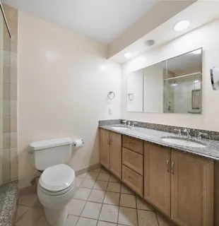a bathroom with a granite countertop toilet sink and mirror