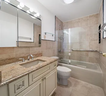 a bathroom with a granite countertop sink a toilet and shower