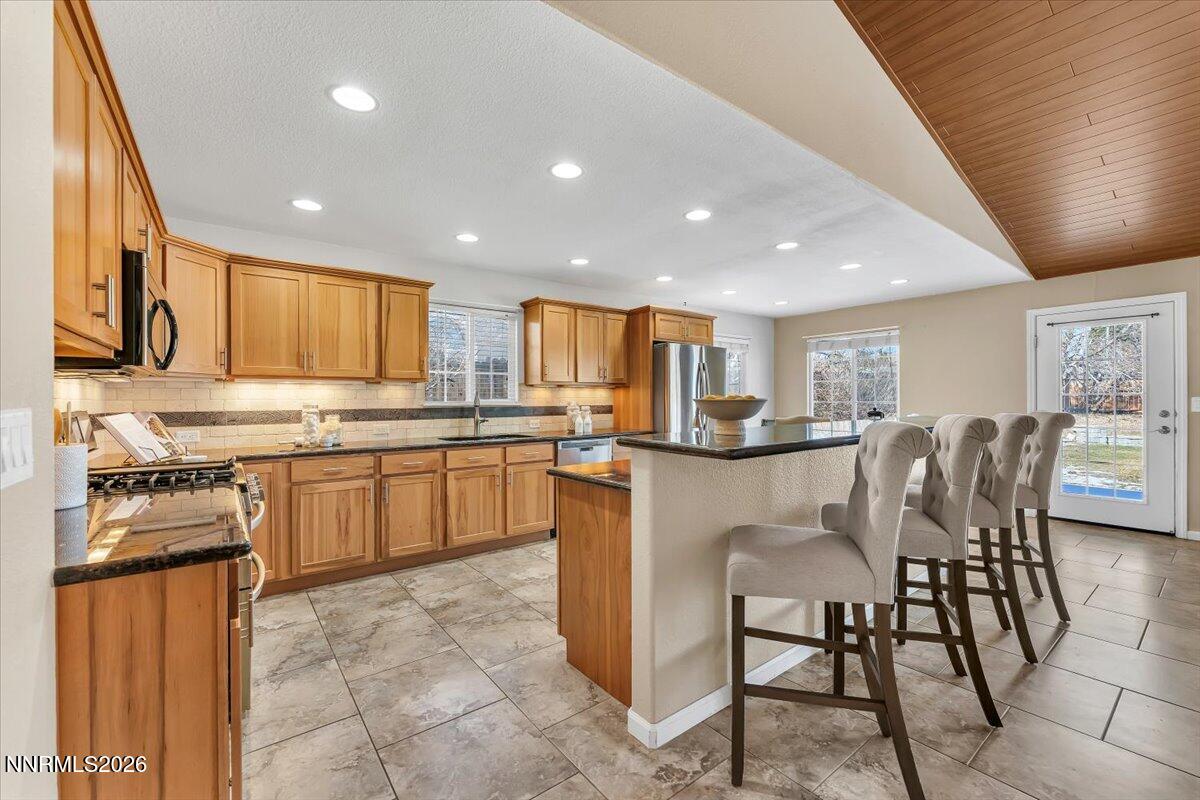 65 Rook Court Sparks, NV 89441 - Photo 15 of 41 a kitchen with kitchen island granite countertop wooden cabinets a stove a microwave a island with a dining table and chairs