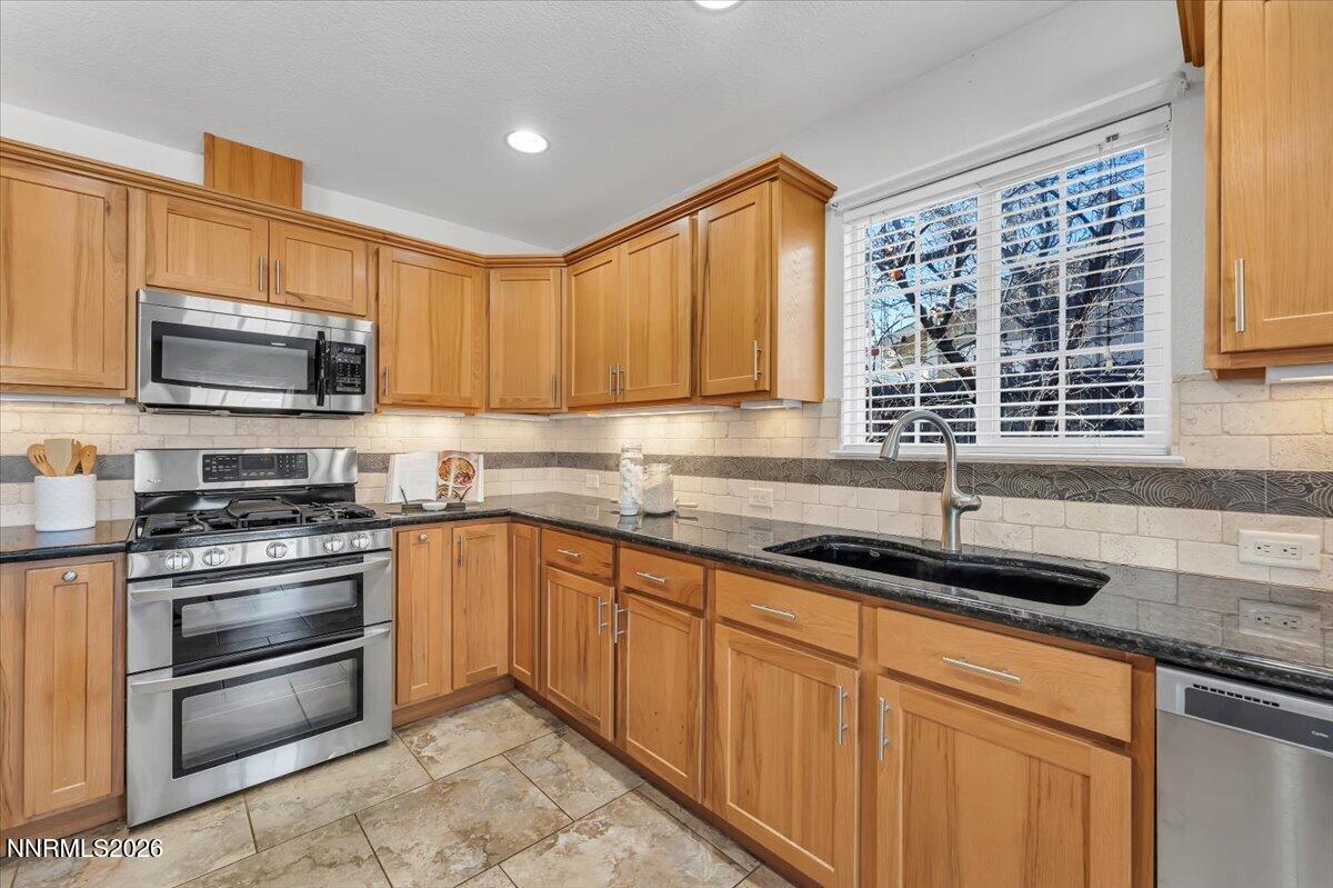 65 Rook Court Sparks, NV 89441 - Photo 18 of 41 a kitchen with stainless steel appliances granite countertop a stove a sink and a microwave