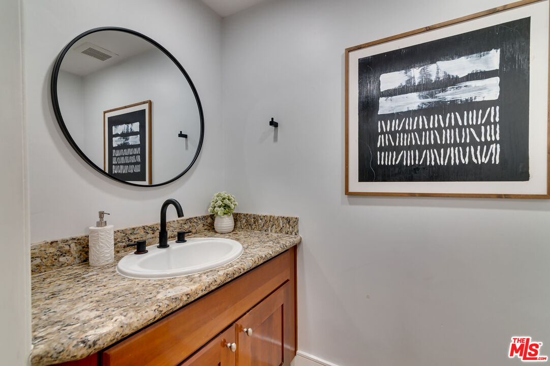 1878 Greenfield Avenue, Unit 104 Los Angeles, CA 90025 - Photo 13 of 35 a bathroom with a granite countertop sink and a mirror