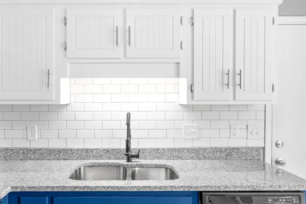 a kitchen with granite countertop a sink and white cabinets
