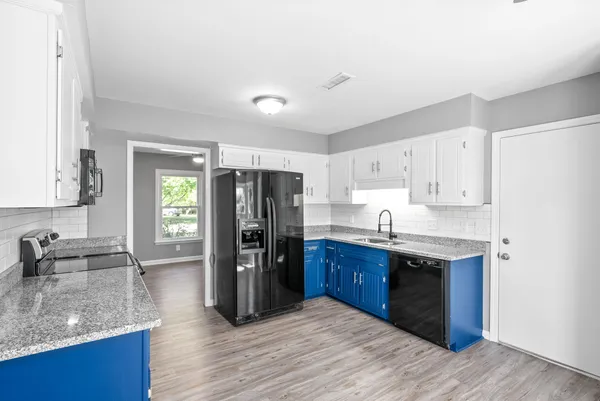 a kitchen with stainless steel appliances granite countertop a refrigerator a sink dishwasher a stove and white countertops with wooden floor