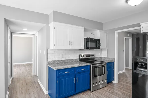 a kitchen with granite countertop a stove and a wooden floor