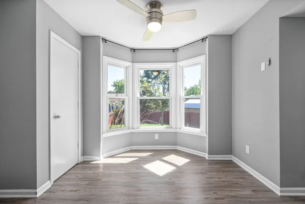 a view of an empty room with a window and wooden floor