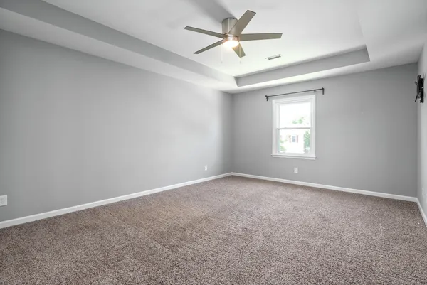 an empty room with a window and a fan