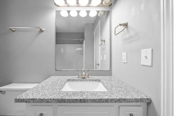 a bathroom with a granite countertop sink and a mirror