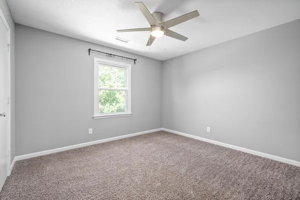 an empty room with a window and a fan