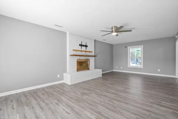 a view of an empty room with window and wooden floor