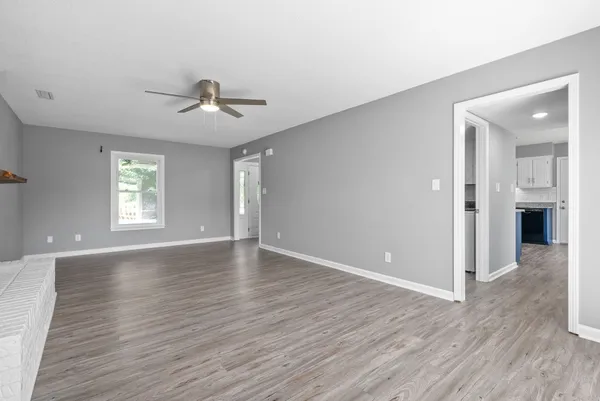 a view of an empty room with window and wooden floor
