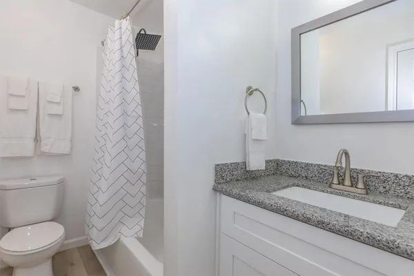 a bathroom with a granite countertop sink toilet and shower
