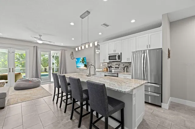 a kitchen with stainless steel appliances granite countertop a table chairs sink refrigerator and microwave