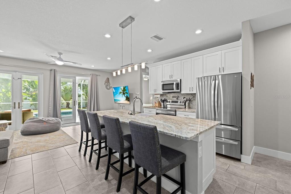 279 Avalon Road Venice, FL 34293 - Photo 15 of 32 a kitchen with stainless steel appliances granite countertop a table chairs sink refrigerator and microwave