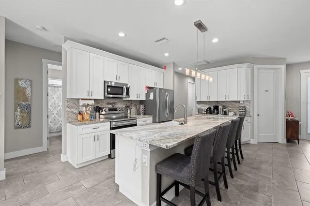 a kitchen with kitchen island a dining table chairs stainless steel appliances and cabinets
