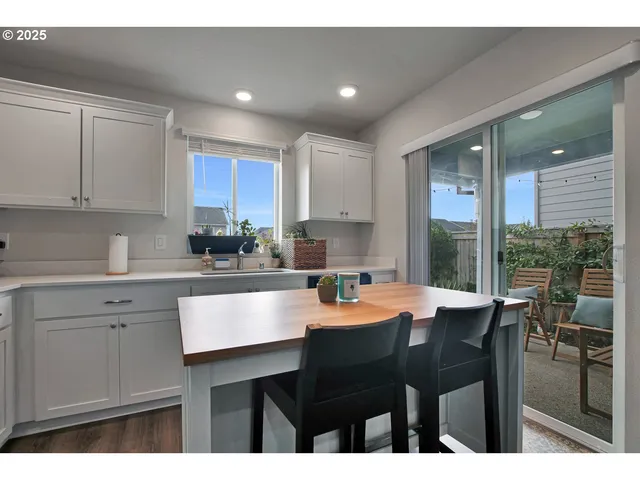 a kitchen with stainless steel appliances granite countertop a table chairs sink refrigerator and cabinets